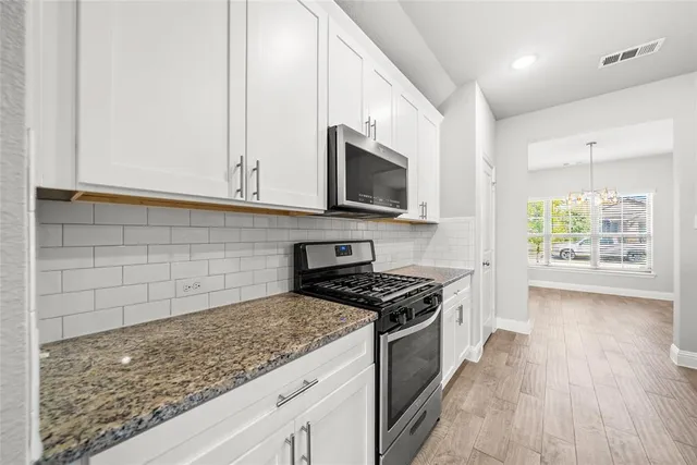 a kitchen with granite countertop a sink a stove top oven and cabinetry