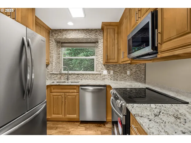 a kitchen with stainless steel appliances granite countertop a sink stove and refrigerator