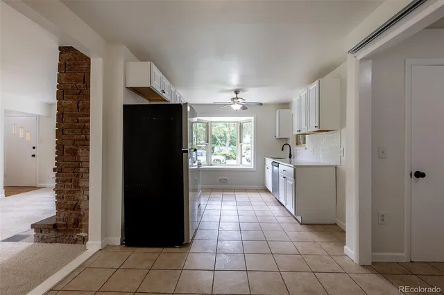 a view of a refrigerator in kitchen and an empty room