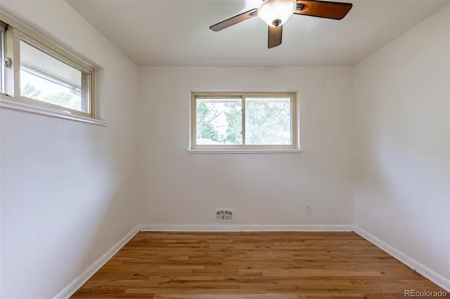 a view of an empty room with window and wooden floor