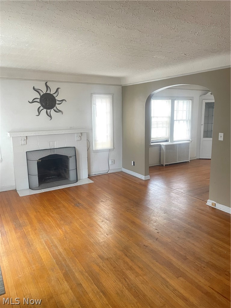 3645 Winchell Road Shaker Heights, OH 44122 - Photo 2 of 37 Unfurnished living room featuring wood-type flooring, a tile fireplace, a textured ceiling, and radiator heating unit