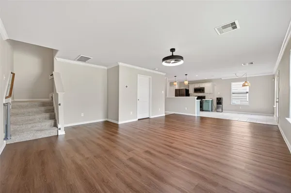a view of a livingroom with wooden floor and kitchen space