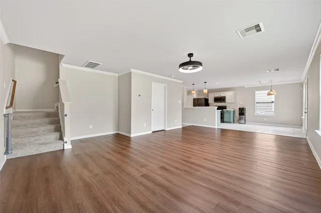 a view of a livingroom with wooden floor and kitchen space