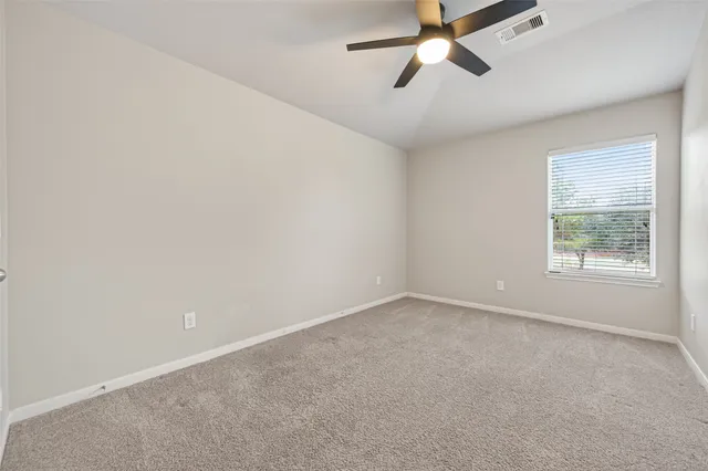 an empty room with a window and a fan
