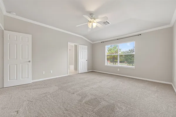 an empty room with chandelier fan and windows