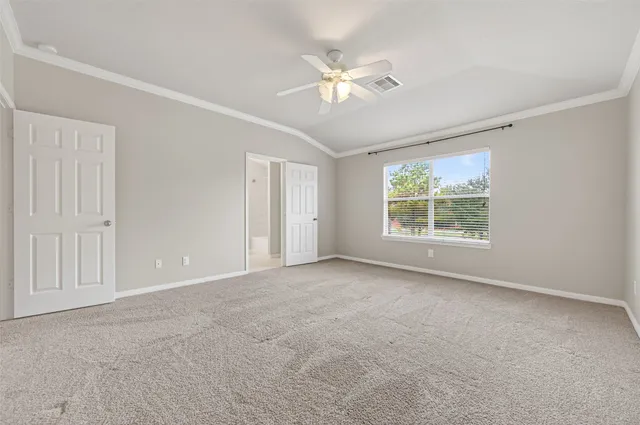 an empty room with chandelier fan and windows