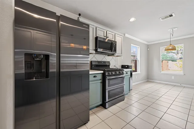 a kitchen with stainless steel appliances granite countertop a refrigerator a stove a sink and a window