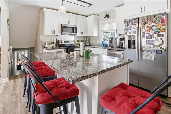 a kitchen with stainless steel appliances granite countertop a table chairs in it and a refrigerator