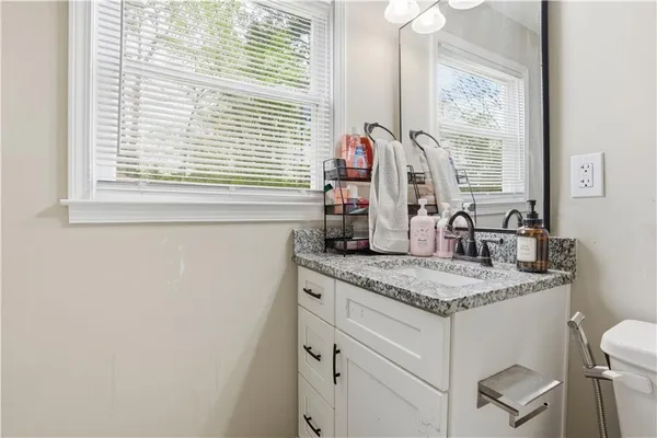 a bathroom with a granite countertop sink and a window