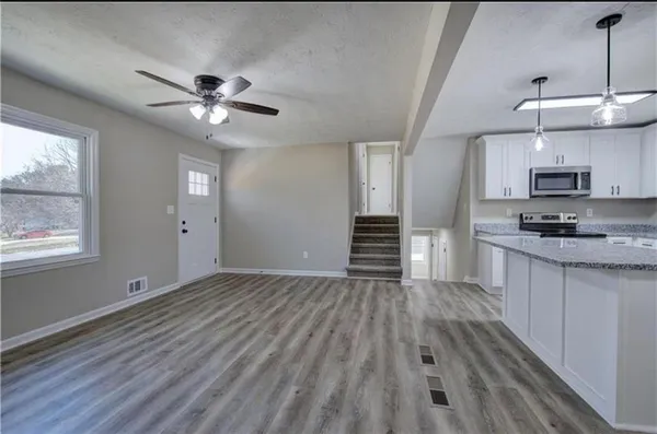 a view of kitchen and empty room with wooden floor