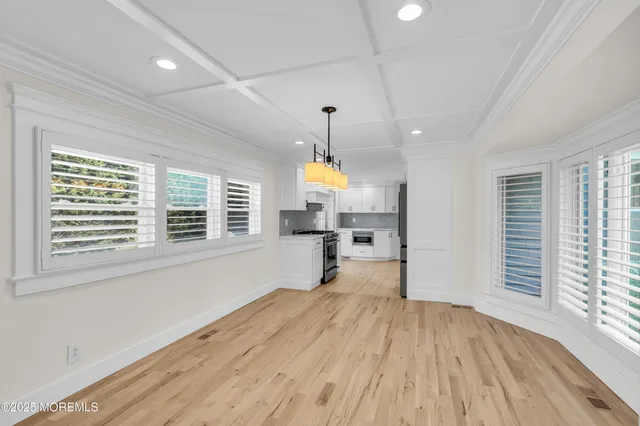 a view of an empty room with wooden floor fireplace and a window