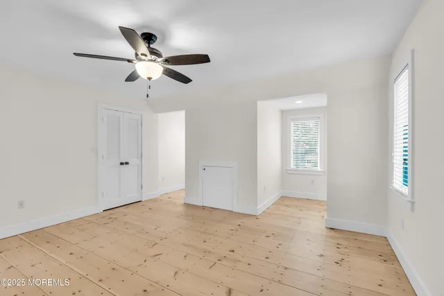 a view of an empty room with wooden floor fireplace and a window