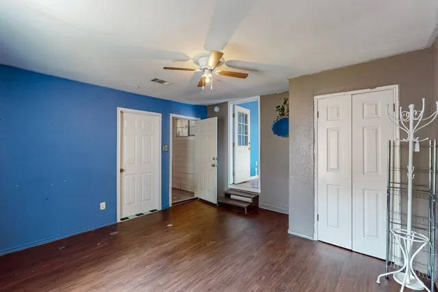 an empty room with wooden floor a ceiling fan and windows