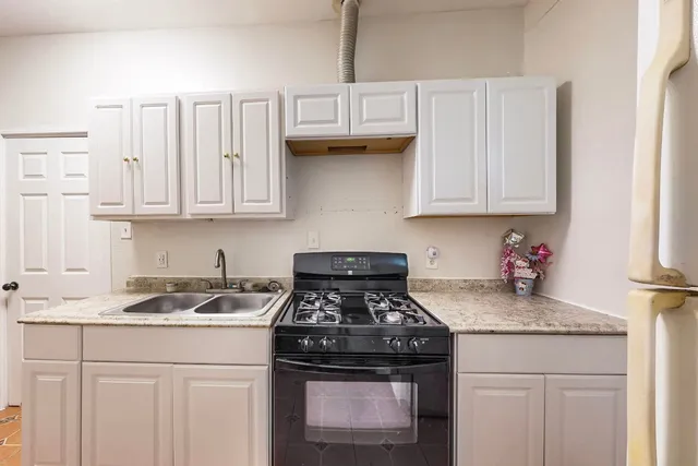 a kitchen with granite countertop white cabinets and a stove top oven