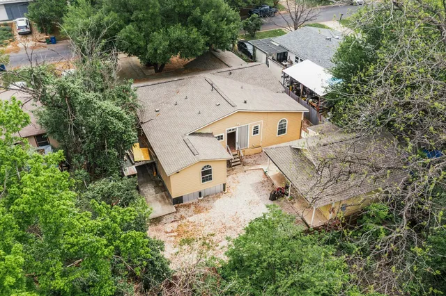 an aerial view of residential house with outdoor space and trees all around