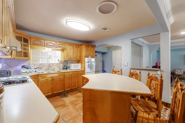 a kitchen with stainless steel appliances granite countertop a stove a sink dishwasher a dining table and chairs with wooden floor