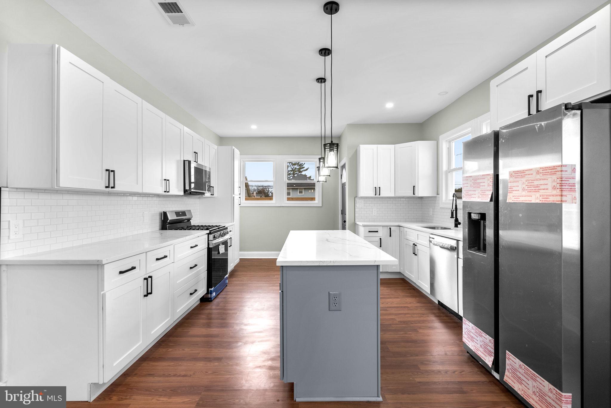 4313 Wentworth Road Baltimore, MD 21207 - Photo 16 of 46 a large kitchen with stainless steel appliances a refrigerator a sink dishwasher a oven and white cabinets with wooden floor
