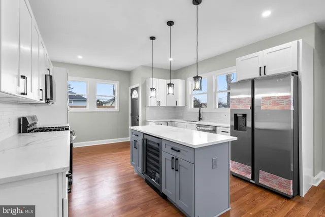 a kitchen with stainless steel appliances granite countertop a refrigerator a sink a stove and a wooden floors