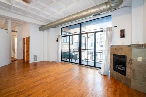 a view of an empty room with wooden floor and a fireplace