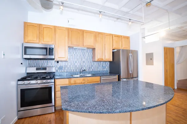 a kitchen with stainless steel appliances granite countertop a stove top oven a sink and a microwave