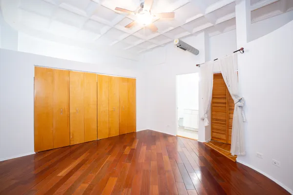 a view of empty room with wooden floor and fan