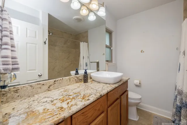 a bathroom with a granite countertop sink a toilet and a mirror