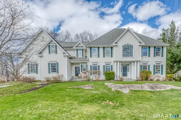 a front view of a house with a garden and trees