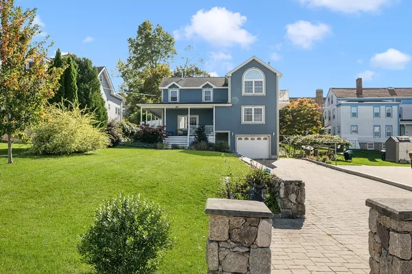 a view of a big yard in front of a brick house with large windows