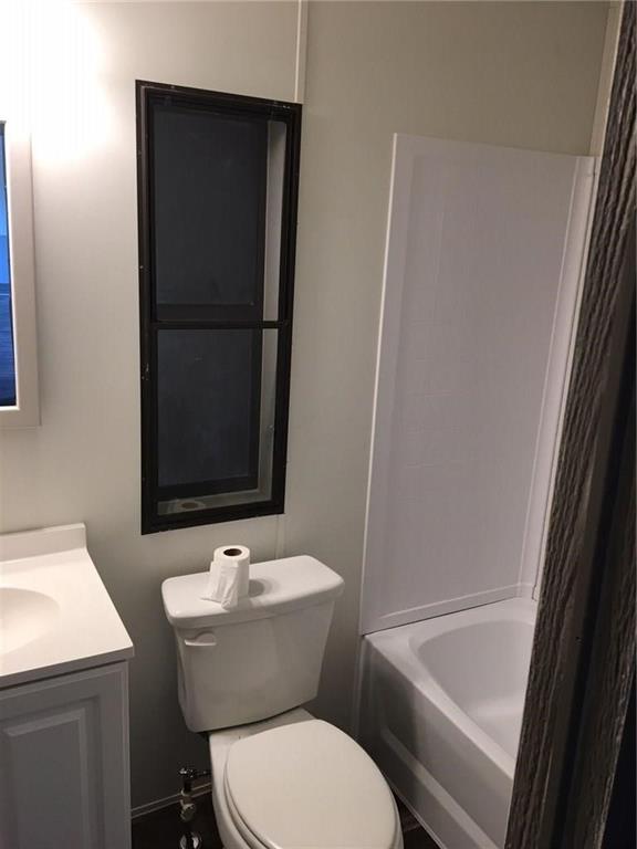 365 Darrell Road Roanoke, TX 76262 - Photo 17 of 22 White vanity with integrated sink, white toilet, white bathtub with wall surround, and dark-framed vertical window