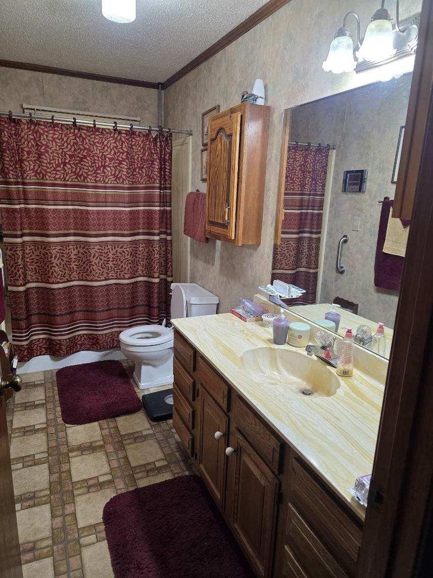 2902 Arp Central Road Ripley, TN 38063 - Photo 11 of 14 Bathroom featuring ornamental molding, vanity, a textured ceiling, a shower with shower curtain, and wallpapered walls