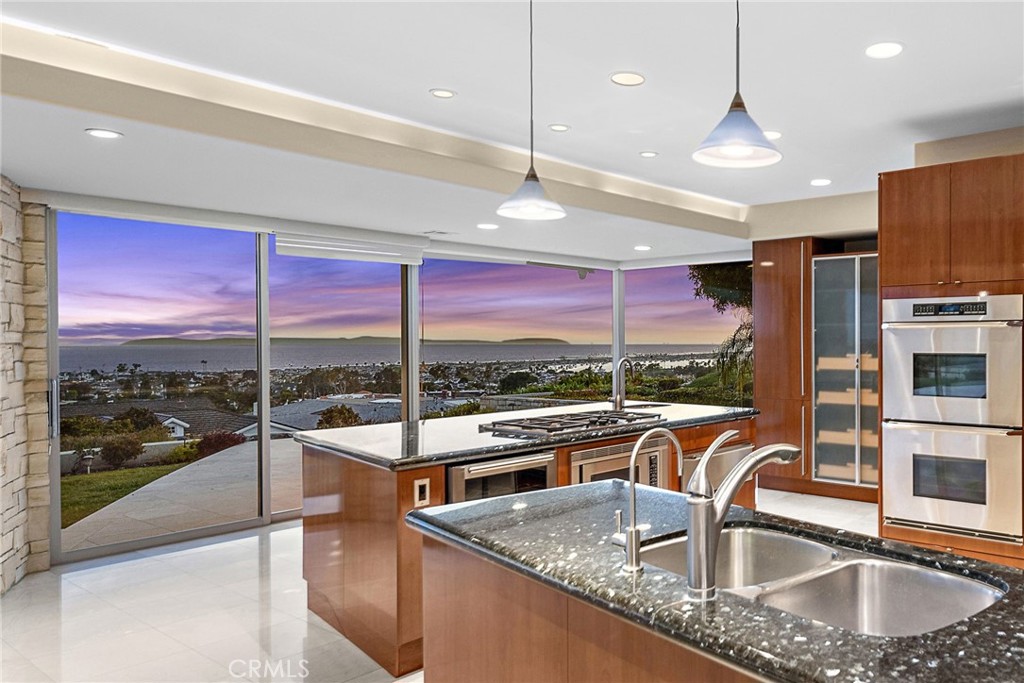 2801 Setting Sun Drive Corona del Mar, CA 92625 - Photo 9 of 30 a kitchen with kitchen island a large window cabinets a sink and stainless steel appliances