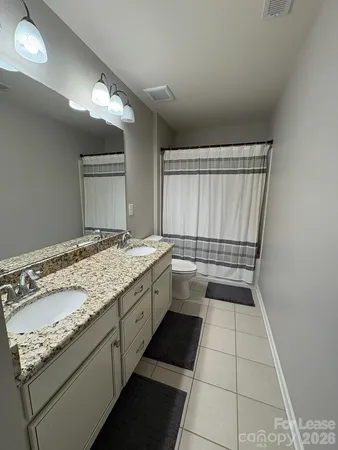 a bathroom with a granite countertop sink a toilet and a mirror