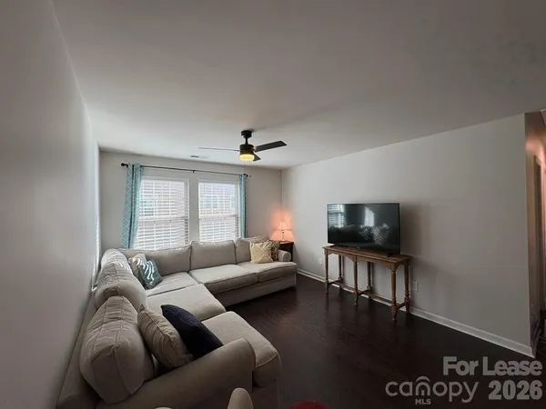a living room with furniture a ceiling fan and a flat screen tv