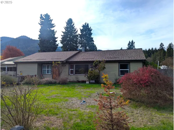 a front view of a house with a garden and trees