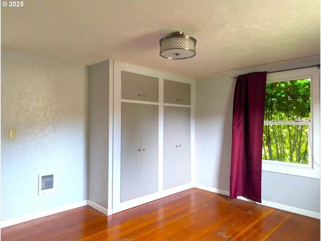 a view of a room with wooden floor and a window