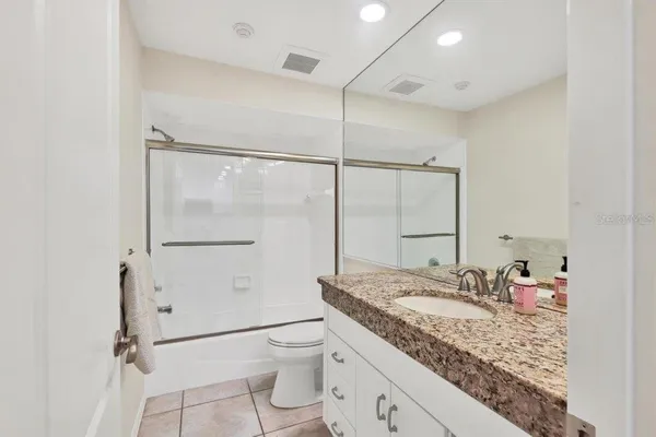 a bathroom with a granite countertop sink mirror vanity and toilet