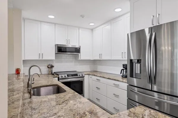 a kitchen with granite countertop a sink stainless steel appliances and cabinets
