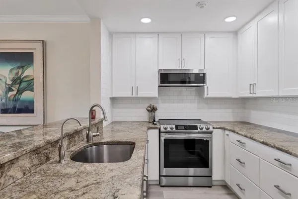 a kitchen with granite countertop a stove a sink and a microwave