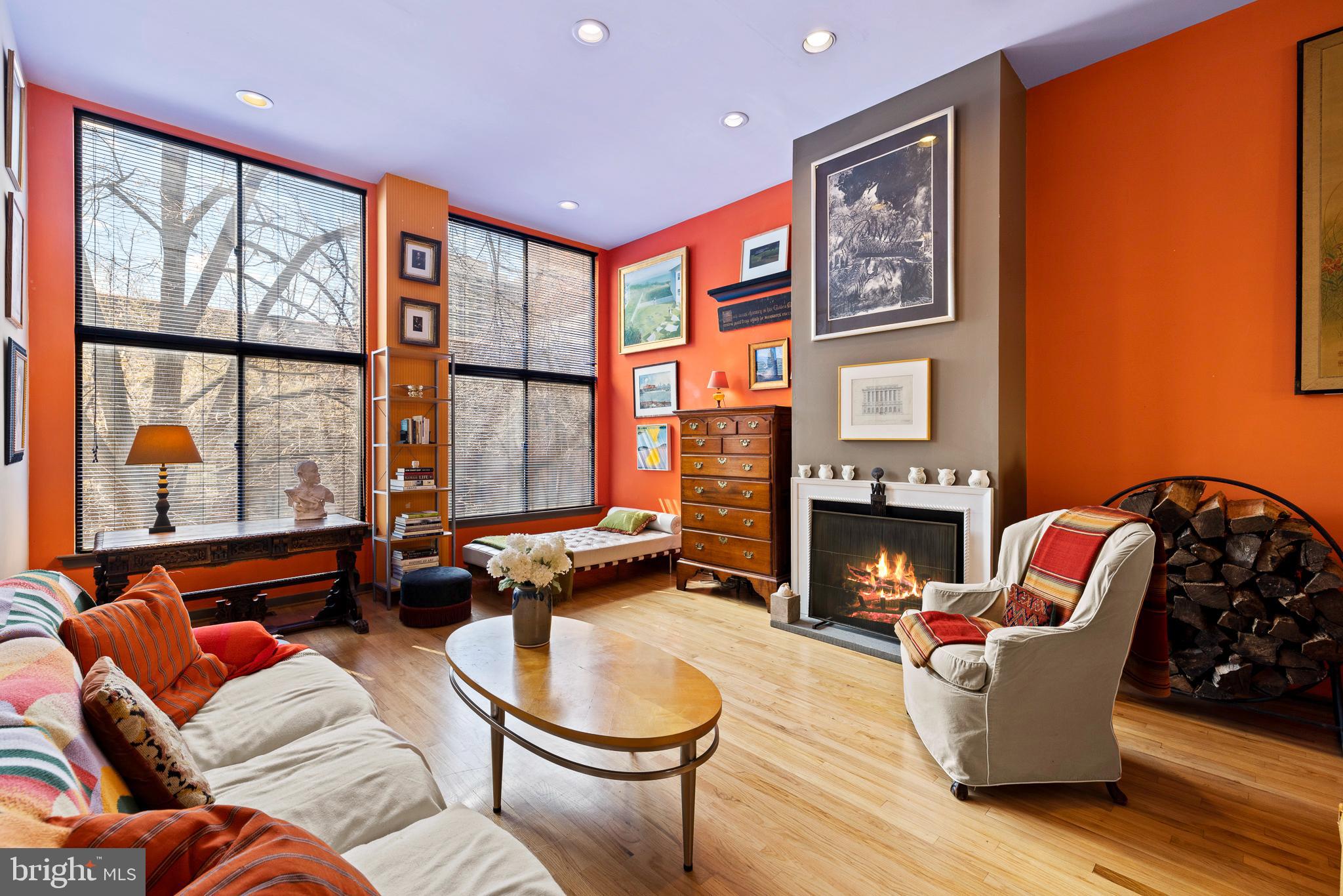 a living room with furniture a fireplace and large windows
