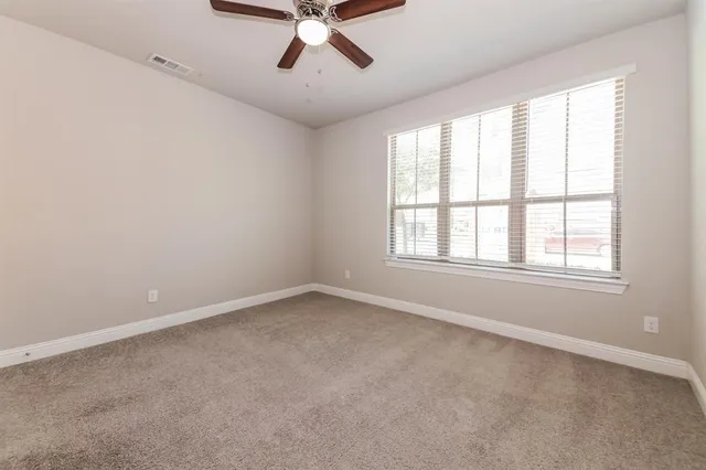 an empty room with ceiling fan and window