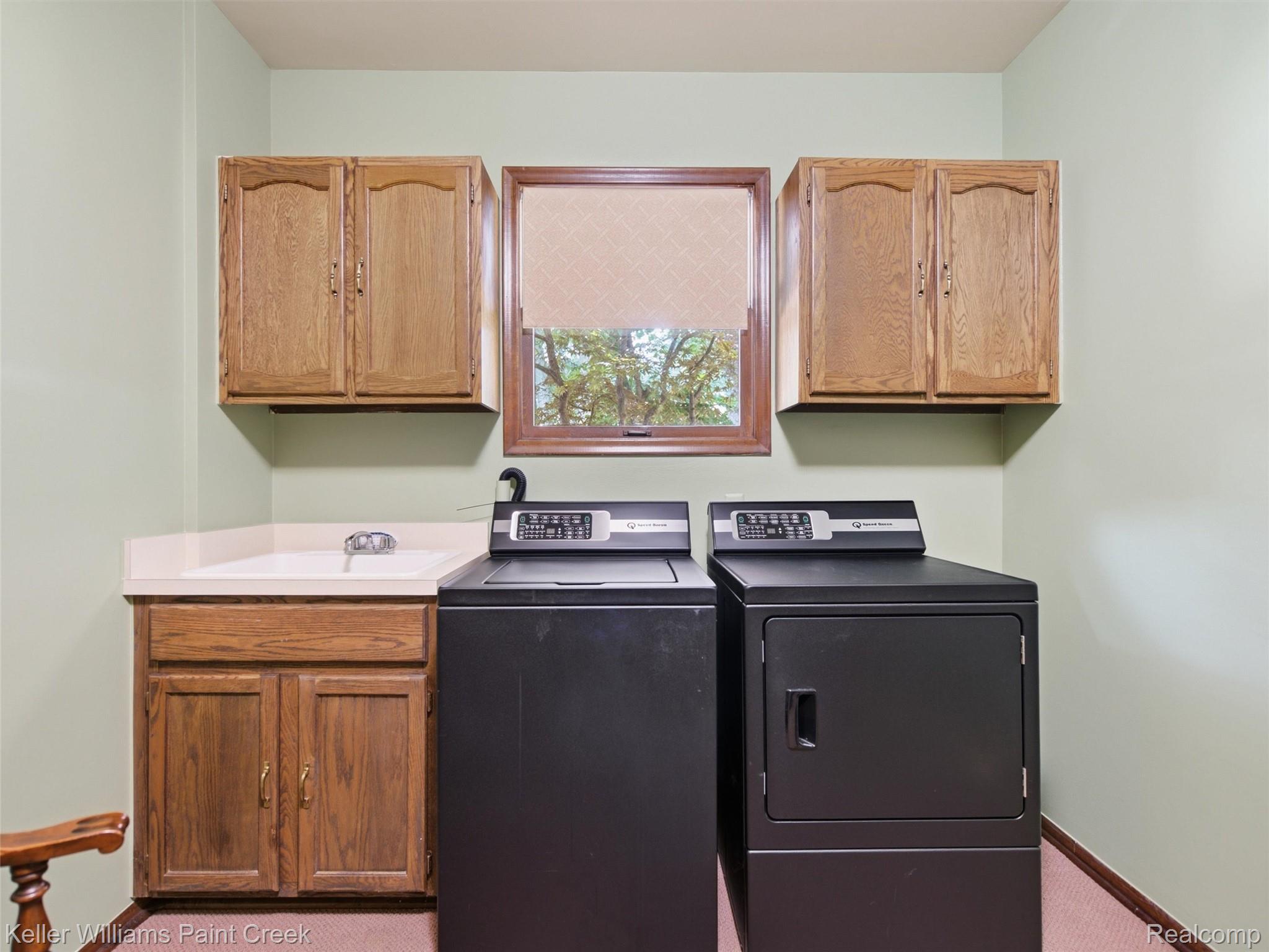 2950 Leyton Court Rochester, MI 48306 - Photo 21 of 46 Laundry area featuring wood cabinetry, a utility sink, and a framed window