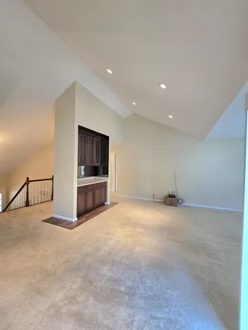 a view of an empty room with kitchen and a window