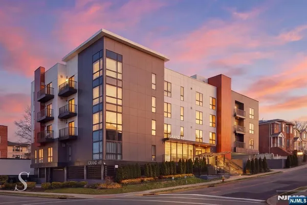 a front view of a building with lot of cars and trees