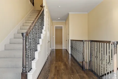 a view of a hallway with wooden floor and stairs