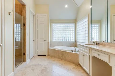 a spacious bathroom with a tub sink shower and mirror