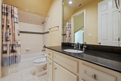 a bathroom with a granite countertop sink a toilet and shower