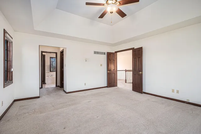 an empty room with windows and fan