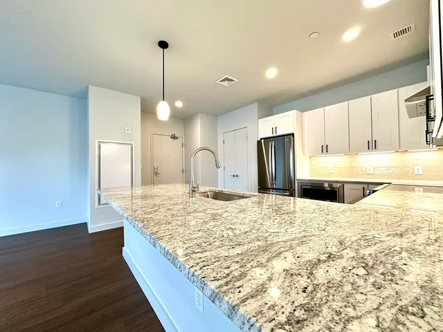 a large kitchen with kitchen island a sink stainless steel appliances and a counter top