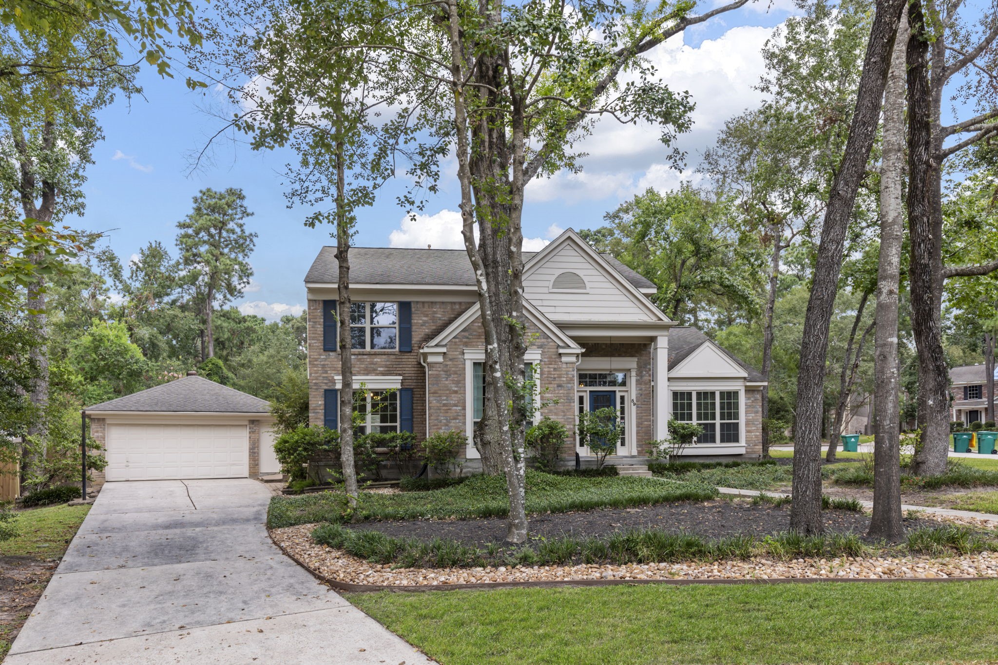 59 Fire Flicker Place Spring, TX 77381 - Photo 30 of 37 Charming two-story home with a brick facade, nestled among mature trees and featuring a long driveway leading to a detached garage, with plenty of space for all your guests.