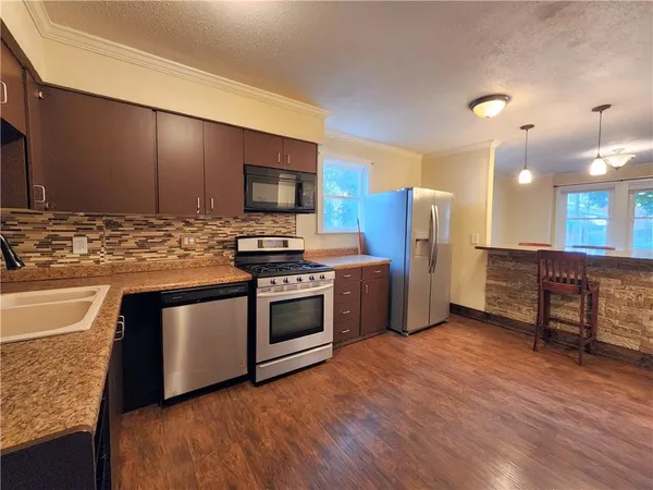a kitchen with stainless steel appliances kitchen island granite countertop a stove a sink and a refrigerator